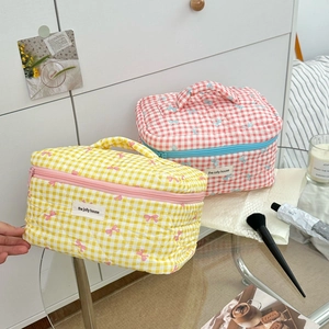 Detailed shot of quilted checkered makeup bags with bow patterns and fabric label