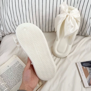 Detail of soft EVA flip-flops with large cream silk bow and anti-slip wavy sole