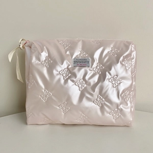 Detail der rosa gesteppten Kosmetiktasche mit geprägten Schmetterlingsmustern und Reißverschluss