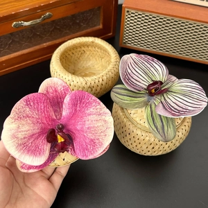 Detail of hand-woven bamboo box featuring elegant faux orchids and fine weaving texture