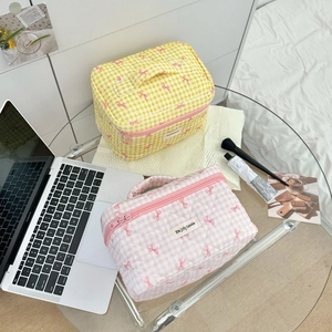 Detail of yellow and pink checkered makeup bags with pink bow accents and hand straps