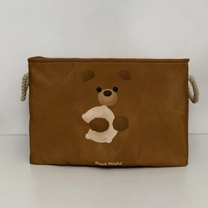 Detailed view of brown canvas storage bin featuring cartoon bear design and thick rope handles