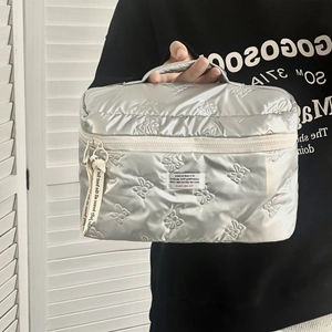 Detail of silver quilted makeup bag with bow pattern and ribbon puller handle