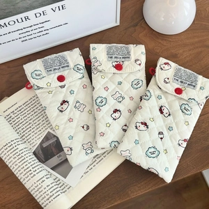 Close-up of quilted cream eyeglass pouch featuring a cartoon cat and red button detail