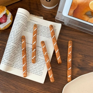Detail view of cute baguette-shaped ceramic coffee stirrers with smiling face patterns