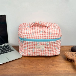 Detailed close-up of a pink checkered quilted toiletry bag with blue bow patterns