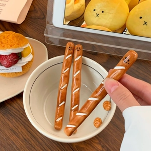Macro detail of cute baguette shaped ceramic coffee stirrers with hand-painted faces