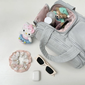 Vue à plat de la trousse de maquillage grise matelassée avec doublure rose et poches