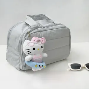 Détail d'une trousse de maquillage grise matelassée avec un porte-clés peluche mignon