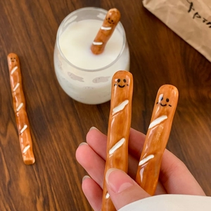 Handheld creative baguette ceramic coffee stirrer with cute smile face on wood table