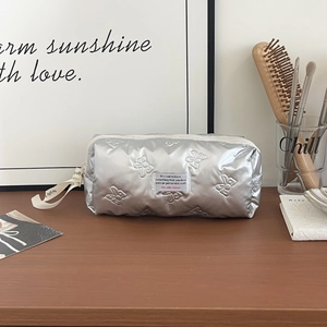 Detailed view of silver quilted makeup bag with bow pattern and metal zipper closure