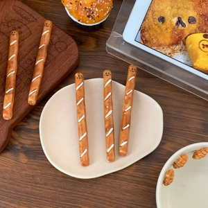 Detail view of five creative baguette-shaped ceramic coffee stirrers with cute faces