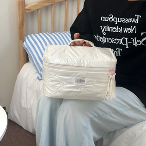 Detail of white quilted cosmetic bag with bow pattern and ribbon handle decoration