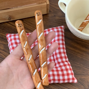 Close-up of baguette-shaped ceramic coffee stirrers with cute smile face design