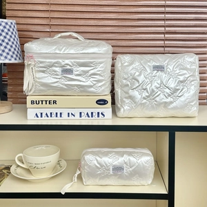 Detailed set of three white quilted bow makeup bags in various sizes with satin finish