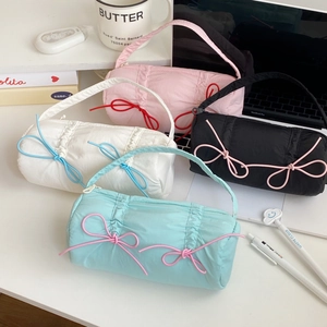 Detailed view of candy-colored quilted pencil cases with bows in four soft pastel colors