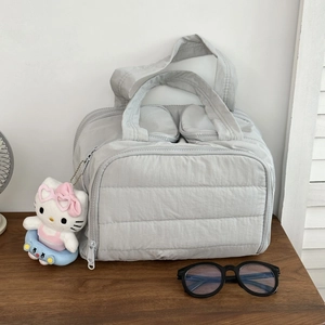 Trousse de maquillage matelassée gris clair avec compartiments zippés sur table en bois