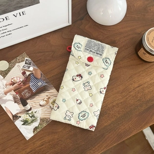 Detailed texture of quilted cream pouch featuring colorful cartoon cat and bear patterns