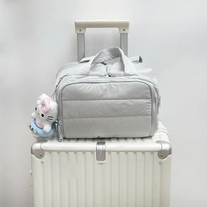 Vue détaillée d'une trousse de toilette matelassée grise avec pendentif sur une valise