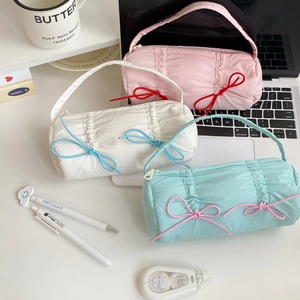 Set of three pastel candy-colored pencil bags with bow details on a white desk
