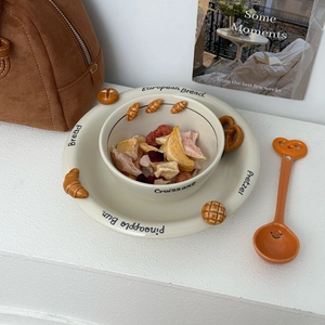 Close-up of ceramic bowl and plate set with embossed croissant and pretzel details
