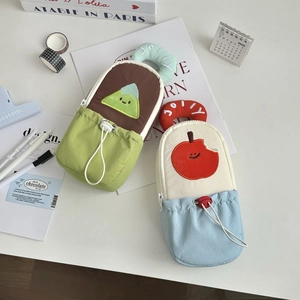 Detail of cartoon fabric stationery bags with mountain and apple embroidery on a white desk