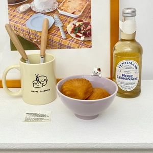 Close-up of a purple ceramic bowl with a cute 3D cat relief and mini madeleine cakes