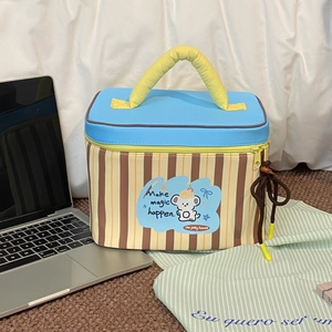 Macro detail of a striped large capacity makeup bag with a blue lid and yellow handle