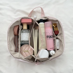 Detailed interior of a double-layer pink makeup bag showing multi-compartment storage