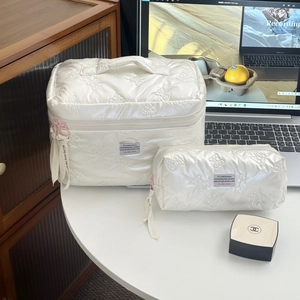 Detail of quilted butterfly cream makeup bag set with top handle and pink zipper