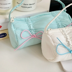 Close-up of quilted puff pencil cases in mint and white with contrasting bow details
