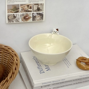 Close-up of cute 3D ceramic cat figurine on cream-colored embossed rice bowl rim