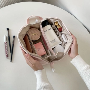 Top view of pink cosmetic bag with interior compartments holding brushes and skincare