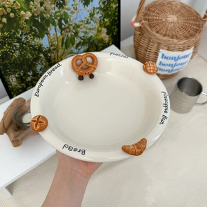 Detail showing embossed ceramic plate with croissant and pretzel patterns on cream surface