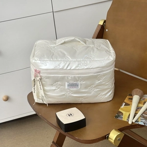 Detail of white quilted makeup bag with bow pattern and contrast pink zipper