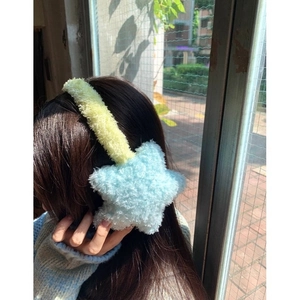 Detail of plush yellow and blue star earmuffs with soft faux fur texture on a model