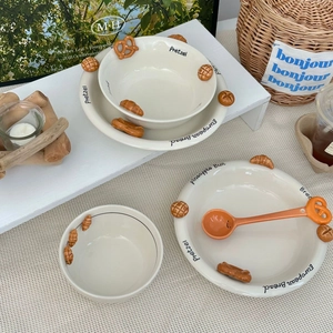 Close-up of ceramic bowl with embossed pretzel detail and matching spoon on table
