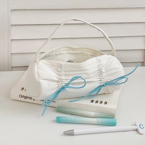 Close-up of white pleated stationery bag with light blue drawstrings on desk