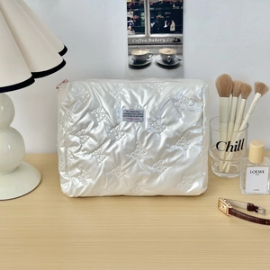 Close-up of pearl white quilted cosmetic bag with cute bow pattern and leather texture