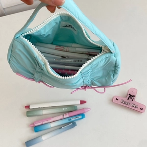 Top view of spacious light blue quilted pencil case filled with colorful pens and white zipper
