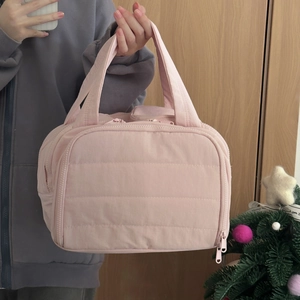 Detail of pink quilted toiletry bag with zipper closure and webbing handle for travel