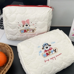 Detail of white quilted cosmetic bag with heart patterns and cute puppy embroidery