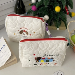 Macro view of white quilted puppy makeup bag featuring red zipper and soft heart texture