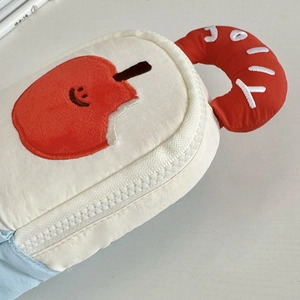 Close-up of plush pencil case with cute apple embroidery and red JOY handle detail