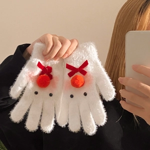 Close-up of white plush gloves with red velvet bows and orange pompom reindeer decor