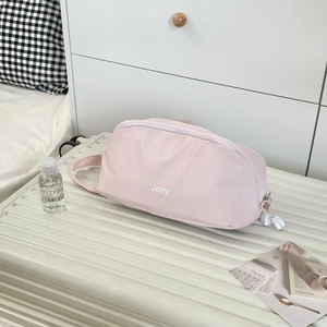 Close-up of pink Jolly cosmetic bag with zipper on a white suitcase in a bedroom