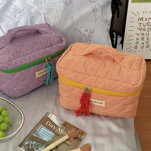 Detailed view of quilted checkerboard cosmetic bags in purple and orange color contrast