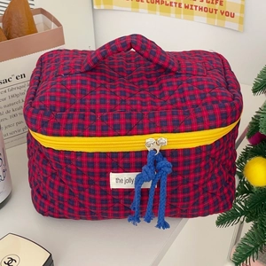 Detail of red and blue checkered quilted bag with yellow zipper and rope puller