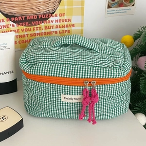 Detail of green quilted checkered makeup bag with pink puller and orange zipper