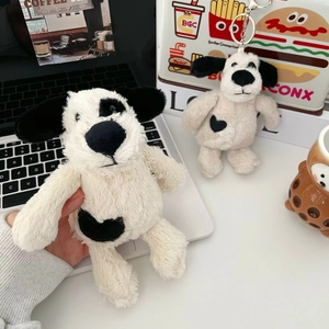 Close-up of plush puppy pendants with heart spots and metal keychains on a desk